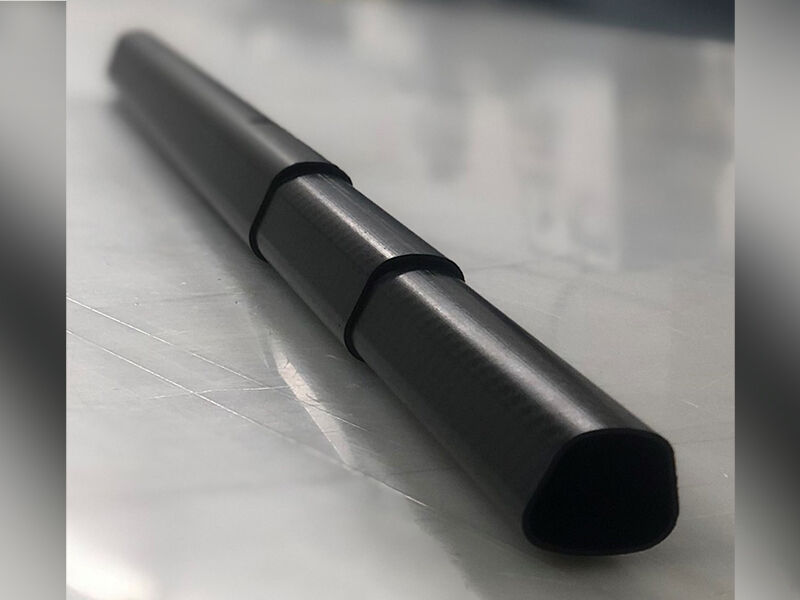 Image of non-cylindrical carbon fiber tubes in telescoping tube formation, expanded to show partial length. The  structure is laid across a white surface.
